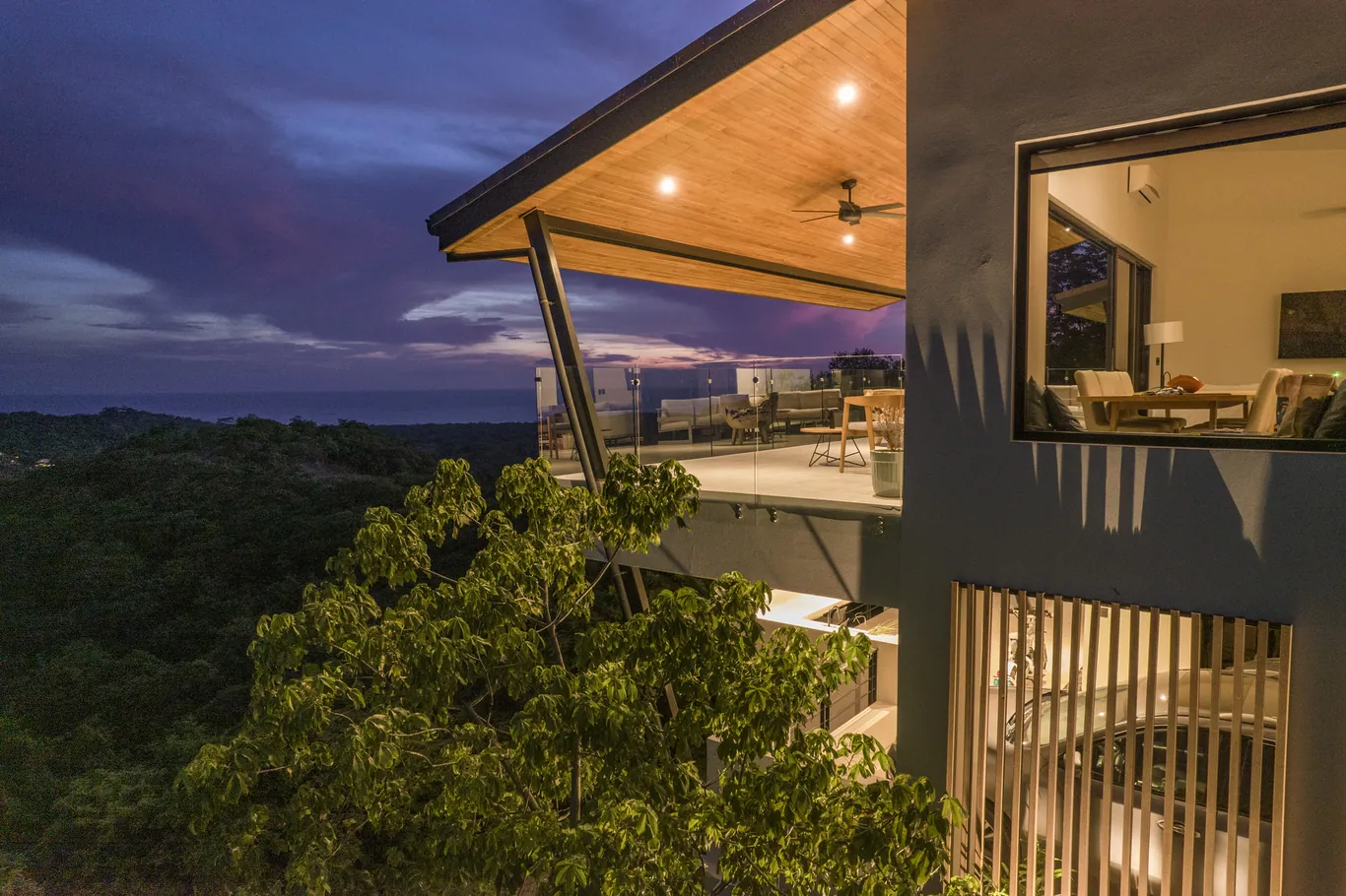 Deep wood-lined eave framing the ocean at nightfall