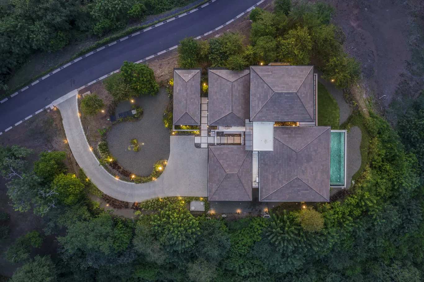Aerial view of a home with a tile roof and pool at night