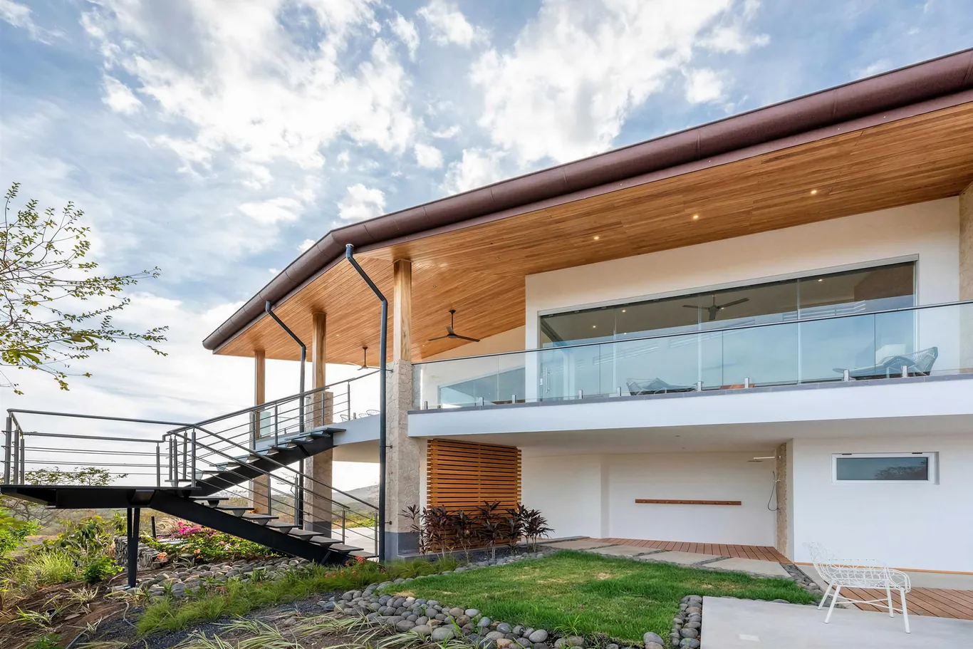 Two-storey home with glass balustrades and wood-lined eaves