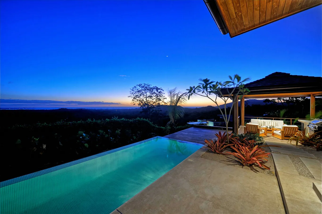 Infinity pool and covered terrace at dusk, ocean beyond