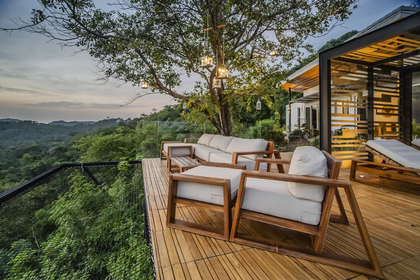 Timber deck and lounge under a tree, forest valley beyond